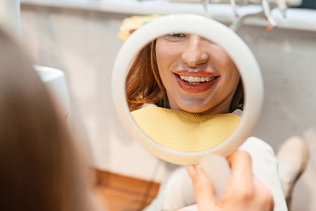 Patient with clear aligners smiling at reflection in mirror