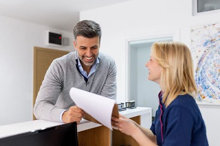 Dental team member assisting patient at front desk