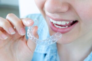 Woman holding Invisalign tray close to her mouth