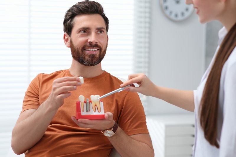 man holding tooth mold with dental implant